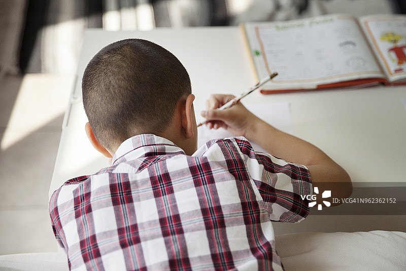 男孩在房子里的桌旁学习的背影图片素材