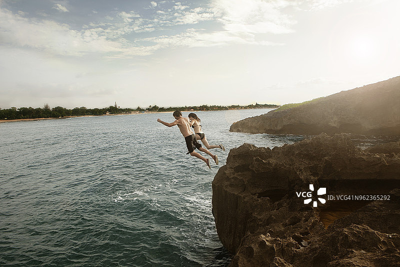 朋友们从悬崖跳入海中的高角度视图图片素材