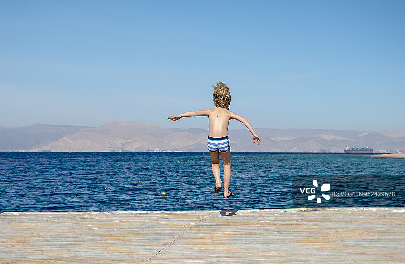 9岁男孩从亚喀巴红海海滩木制码头跳下（约旦）图片素材