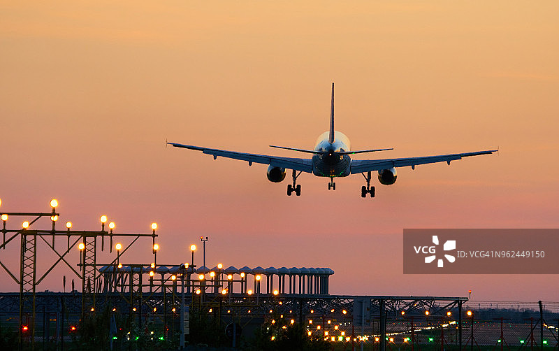 日落时分在巴塞罗那机场降落的飞机图片素材