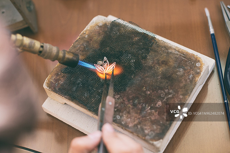 女人在工作室里拿着焊枪熔化银图片素材