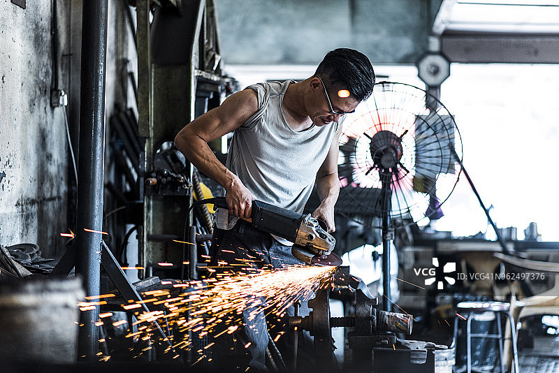 使用砂轮机的亚洲铁匠图片素材