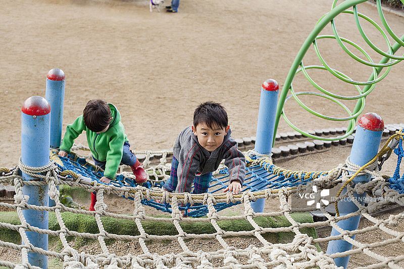 男孩们在游乐场的网上攀爬（高角度）图片素材