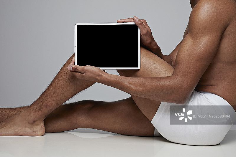 男人把平板电脑放在膝盖前图片素材