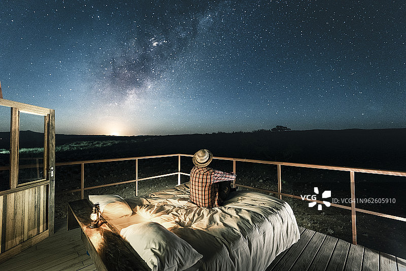 坐在星空下的户外床上的游客图片素材