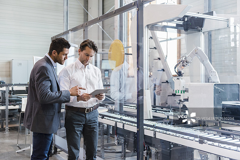 两位商人在现代工厂用平板电脑交谈图片素材
