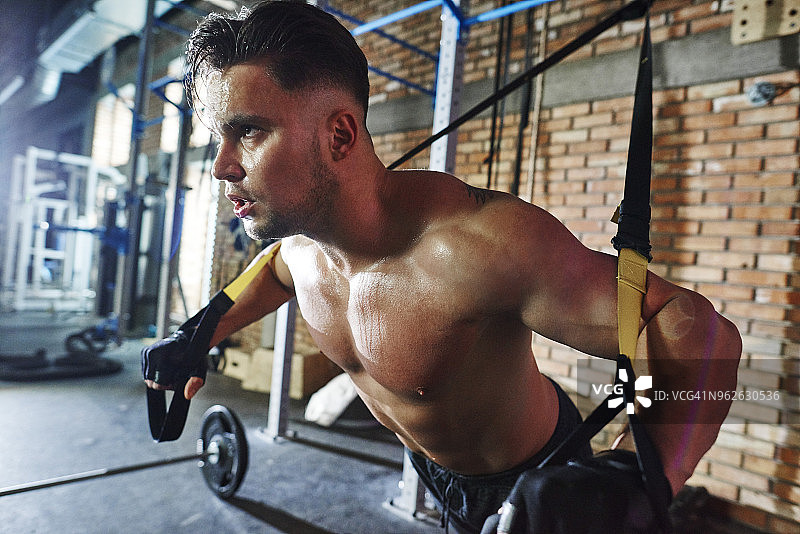 男人在健身房用悬挂带做运动图片素材