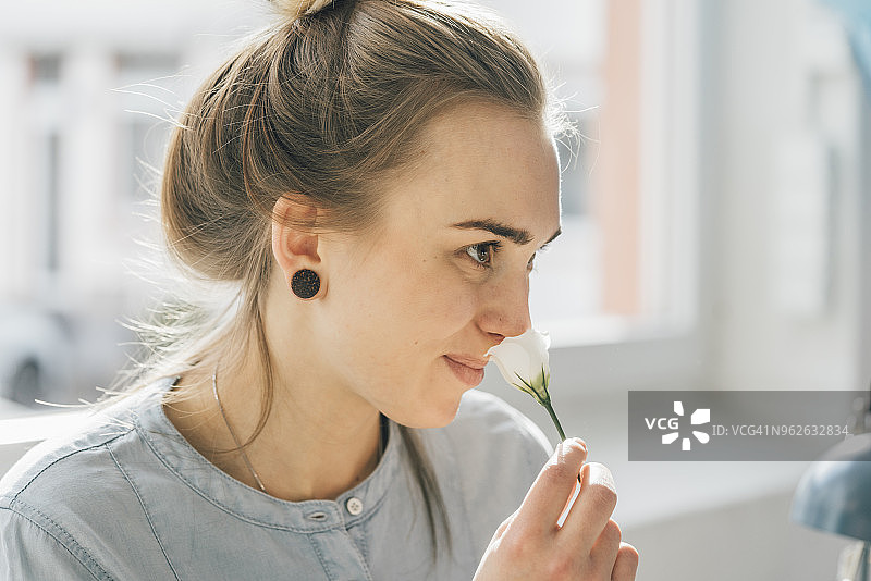 微笑的年轻女子在闻花香图片素材