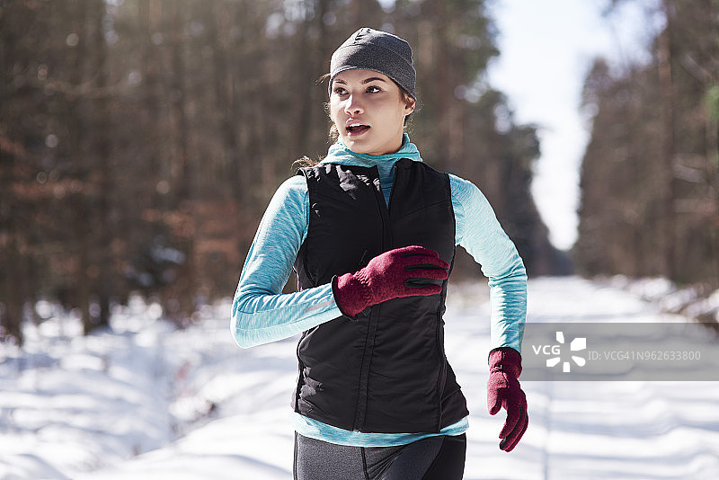 在冬季森林中慢跑的年轻女性肖像图片素材