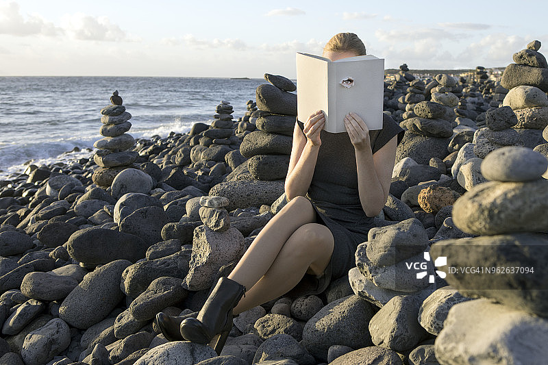 女人用书遮住脸，读诗，眼睛透过封面看图片素材