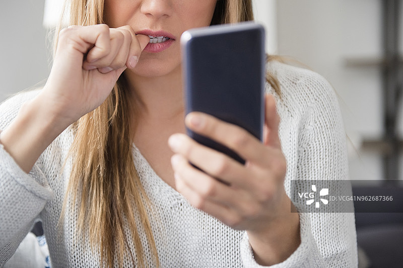 紧张的年轻女子正在使用智能手机图片素材