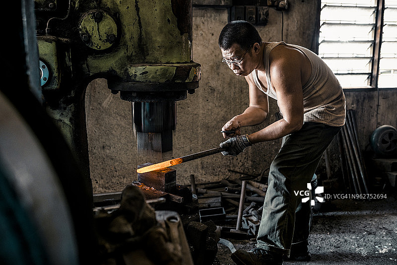 铁匠用液压机锻造铁块图片素材