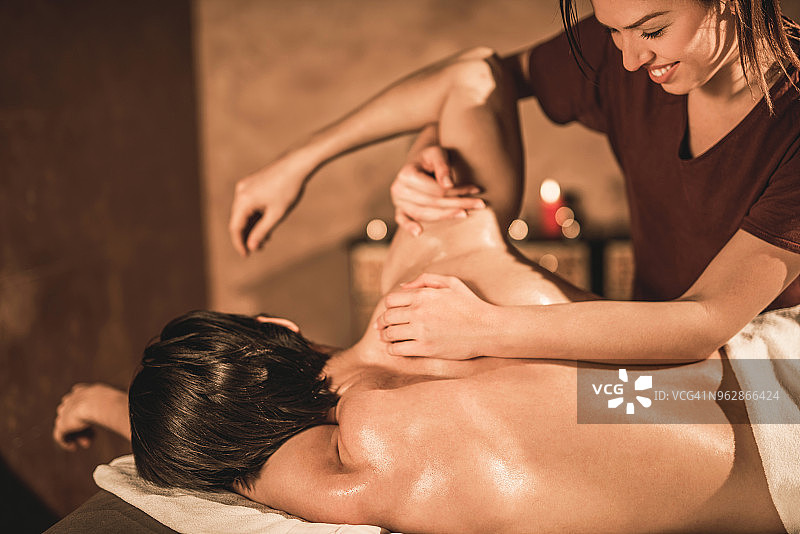 快乐的女按摩治疗师为受伤的年轻男运动员治疗图片素材