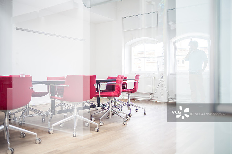 在办公楼会议室使用手机的商人剪影（玻璃视角）图片素材