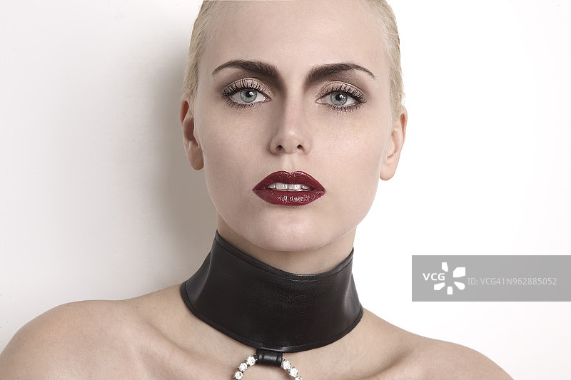 画着蓝色眼睛、红色口红、戴着时尚皮革项圈的女人肖像图片素材