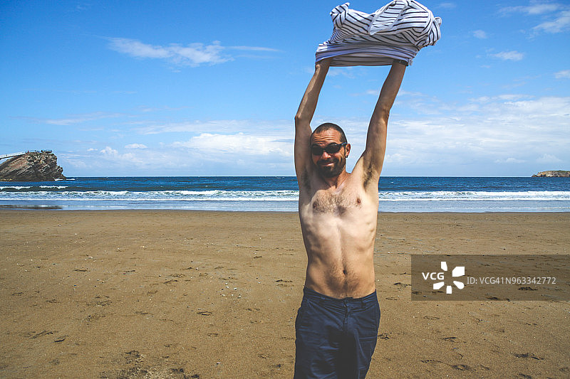 男子在海滩上脱下衬衫图片素材