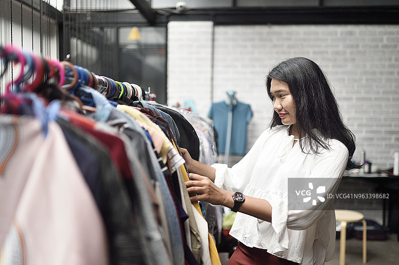 在工作室浏览衣架的马来西亚妇女图片素材
