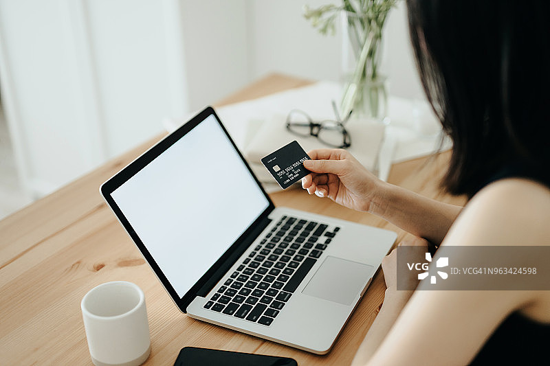在家使用信用卡和笔记本电脑在线支付账单的女人图片素材
