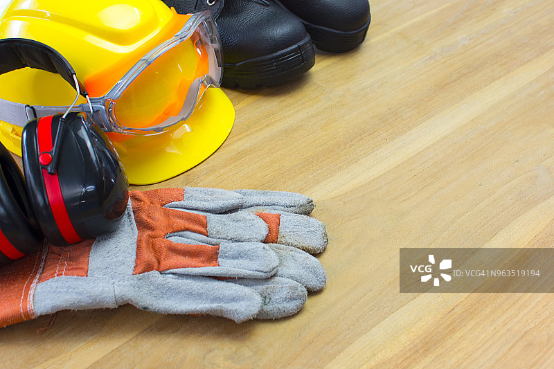 木板上的安全手套、防水工靴和耳罩图片素材