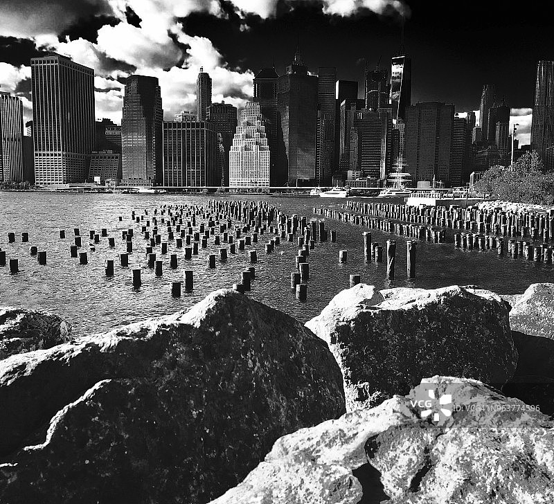 布鲁克林拍摄的曼哈顿市中心、纽约港和巨石的戏剧性黑白低角度视图。图片素材