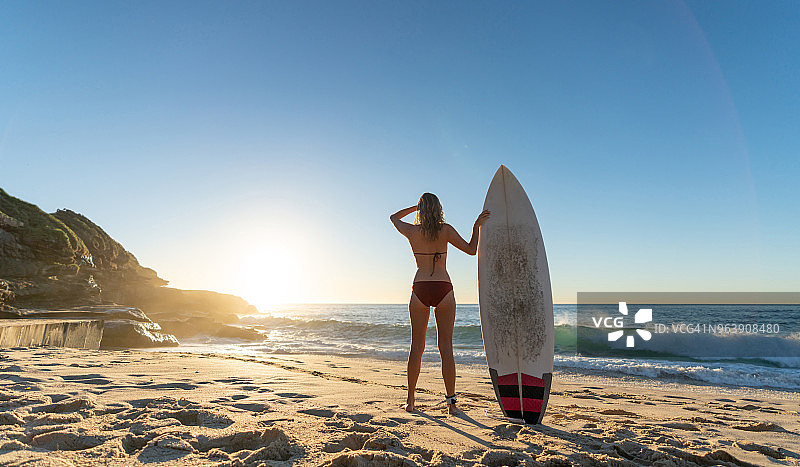 女冲浪者拿着冲浪板观看日出图片素材
