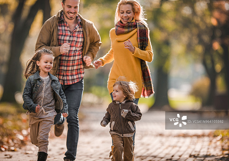 在公园里追逐儿女的年轻幸福的父母图片素材