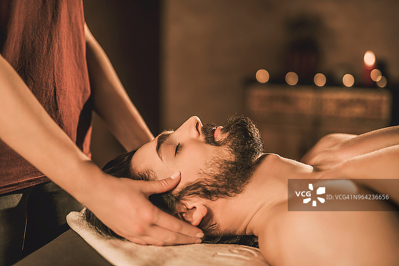 放松的年轻男人享受头部按摩侧视图图片素材