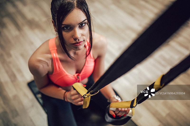 在健身房用悬挂带锻炼的女人图片素材