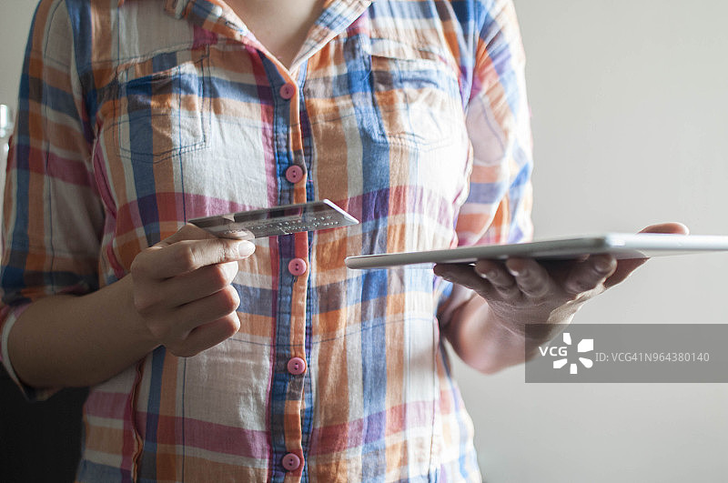 年轻女子正在使用信用卡和平板电脑图片素材