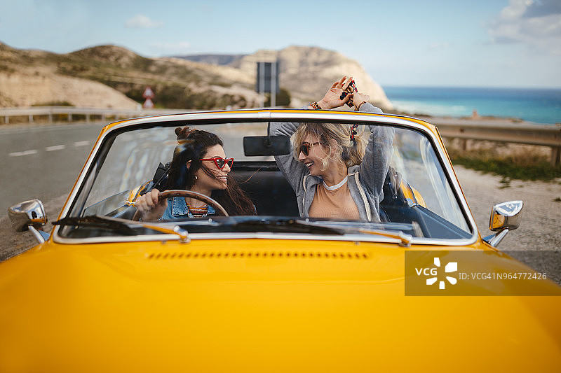 年轻时尚女性在公路旅行中驾驶敞篷车图片素材