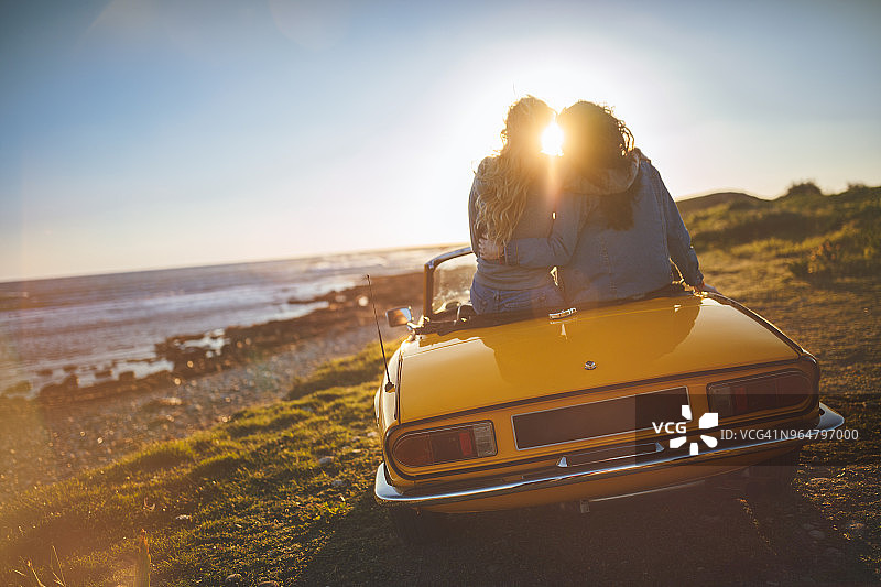 女士们在日落时分在海滩上乘坐敞篷车放松图片素材