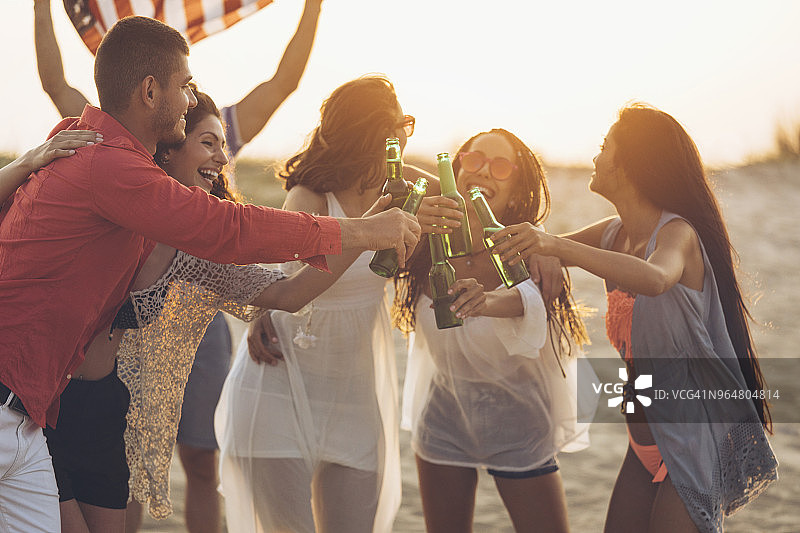 朋友们在沙滩上喝啤酒欢呼图片素材