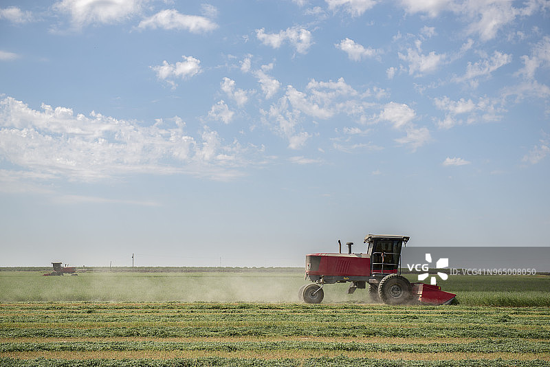 拖拉机在多云天空下耕作图片素材