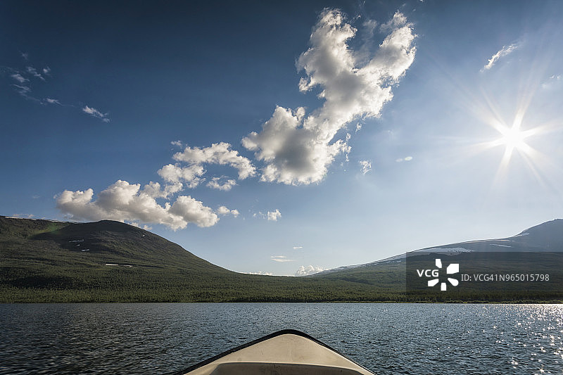 阳光明媚的日子里，湖边田野中的船只的局部照片图片素材