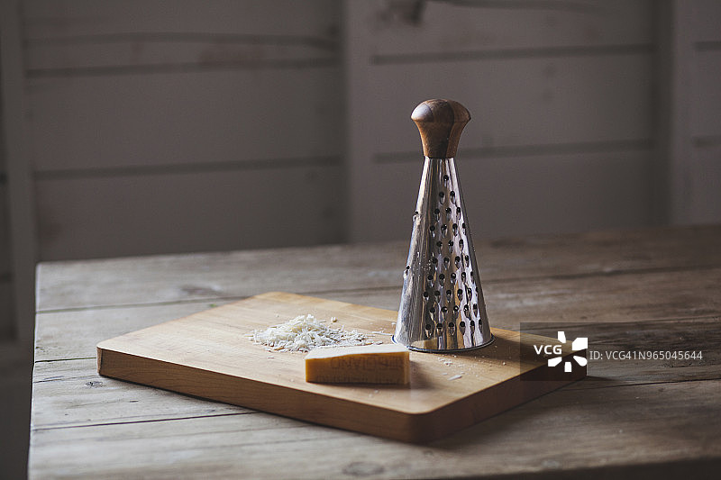 奶酪与刨丝器置于木桌砧板上图片素材