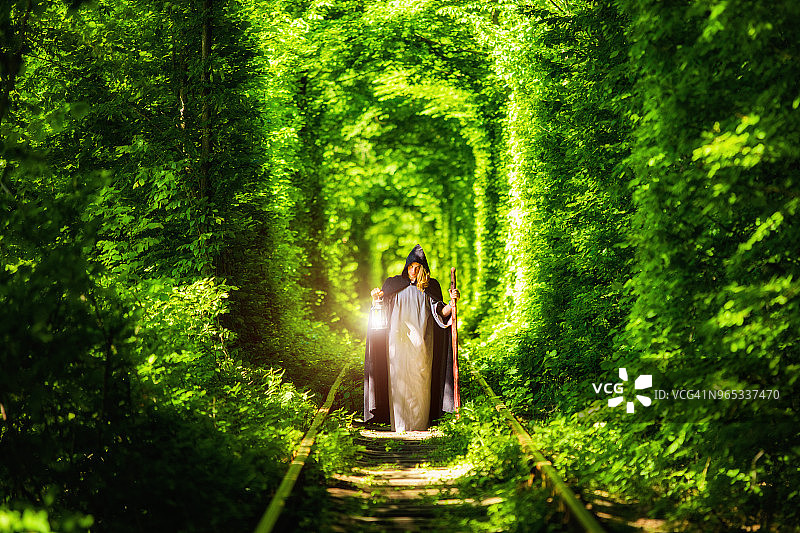 在绿色森林隧道中拿着灯笼的男巫图片素材