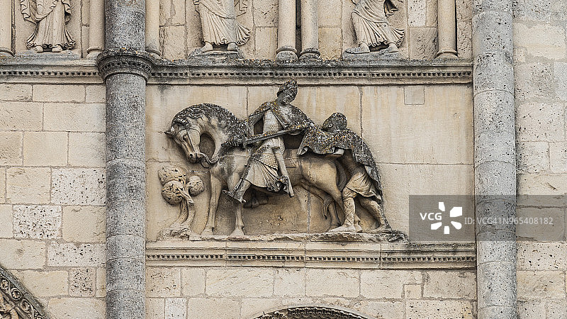 马丁斗篷的传说 - 圣马丁的慈善 - 昂古莱姆大教堂外墙上圣马丁与乞丐分享斗篷的雕塑，法国图片素材