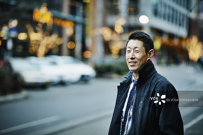 微笑的男商人站在城市街道上等候下班后的汽车图片素材