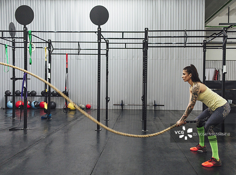 运动员在健身房做战绳运动的侧视图图片素材