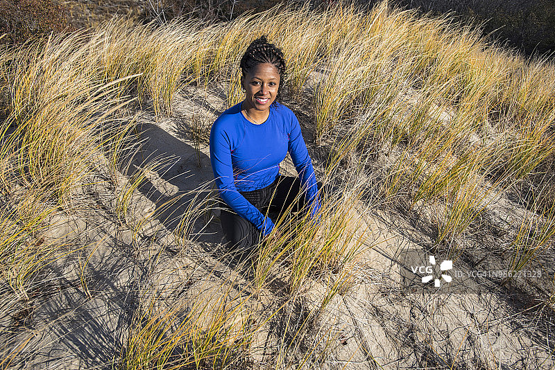 年轻女人坐在沙滩上，美国马萨诸塞州纽伯里波特图片素材