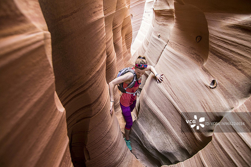 女子在狭窄的斑马峡谷中进行峡谷探险,位于美国犹他州大阶梯-埃斯卡兰特国家纪念地图片素材
