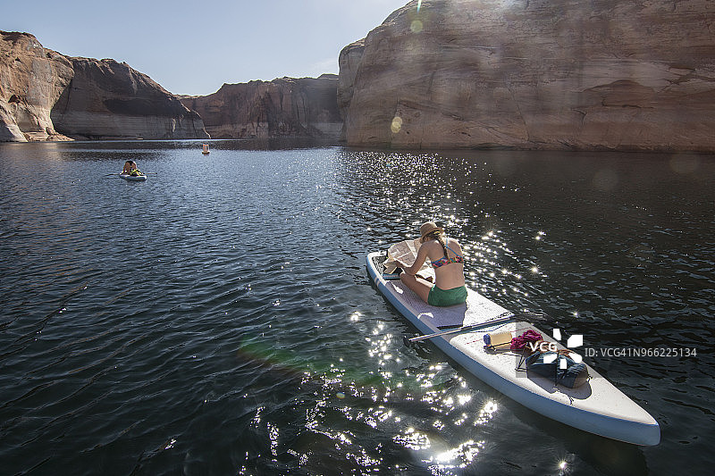 美国犹他州鲍威尔湖上划桨板看地图的女人图片素材