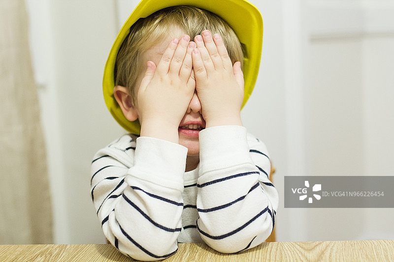 顽皮的男孩在家玩耍时用手捂住眼睛图片素材