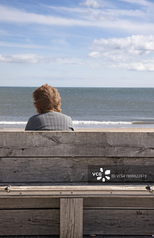 坐在长椅上看着水面的女人图片素材