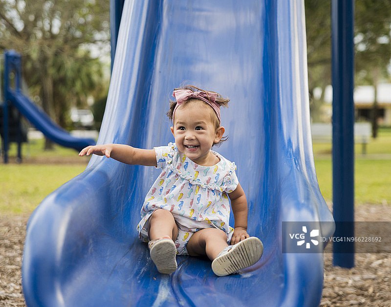 在游乐场滑滑梯的可爱女宝宝图片素材
