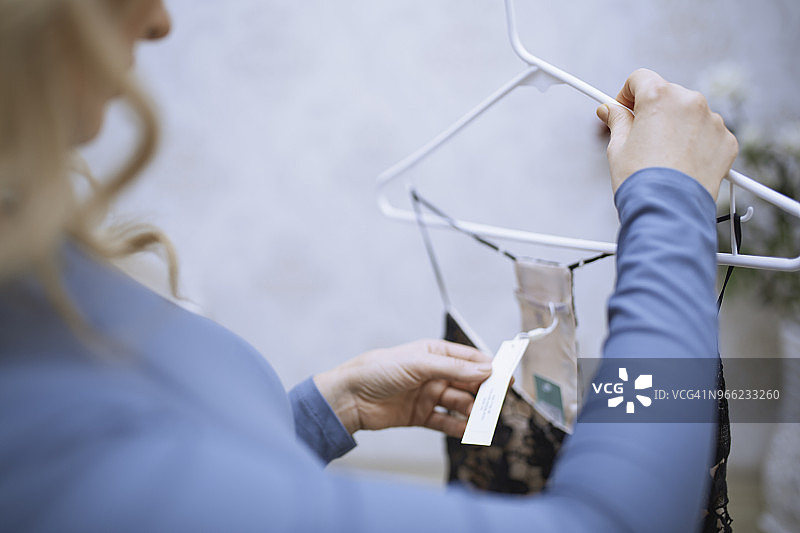 顾客在精品店查看连衣裙的价格标签图片素材