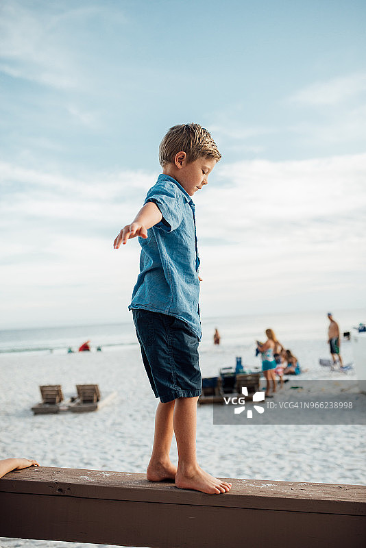 男孩张开双臂走在巴拿马城海滩的木板上图片素材