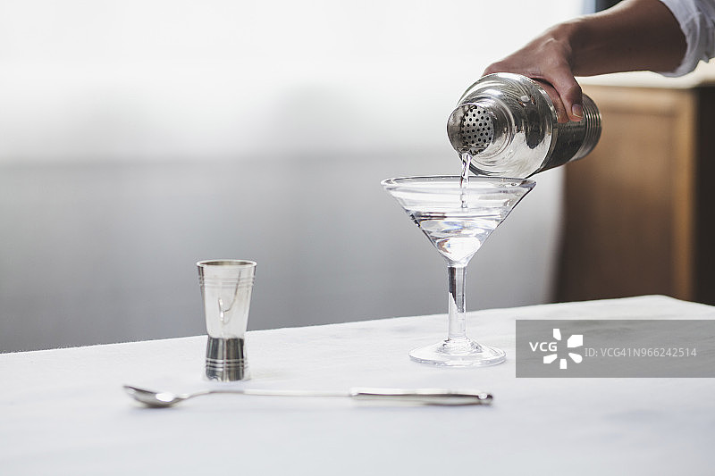 女子手持马提尼酒杯倒入酒精的局部影像图片素材