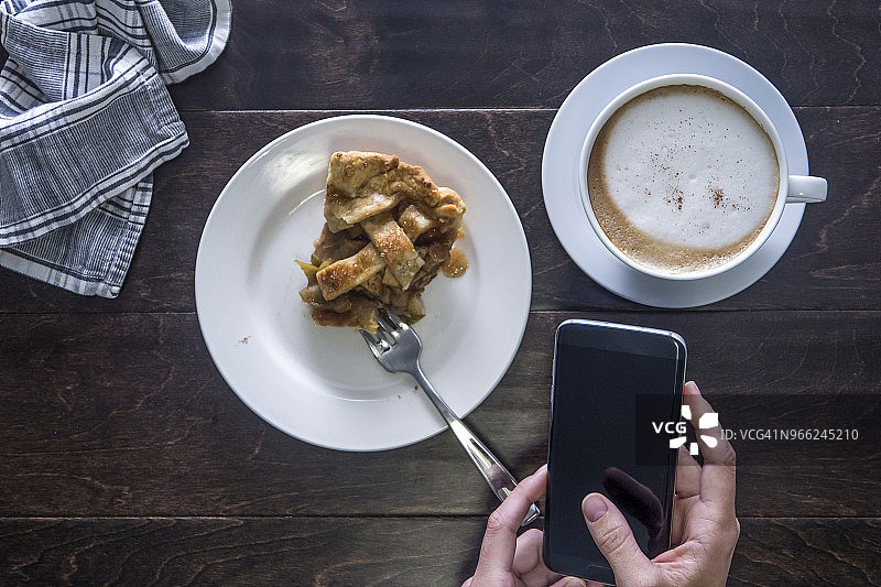 在餐桌旁用智能手机的双手图片素材