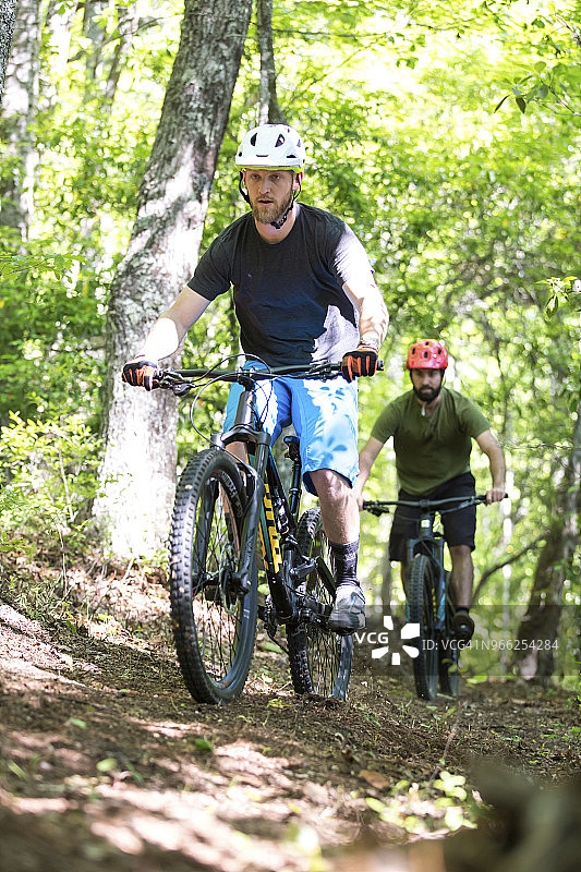 男性朋友在森林的泥路上骑山地自行车图片素材